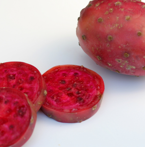 Whole and sliced prickly pear fruit showing deep pink flesh on a white background