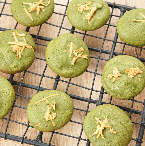 Green tea cookies topped with golden shreds on a wire cooling rack