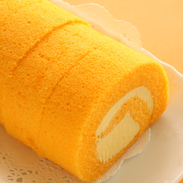 Golden mango Swiss roll with a spiral of cream filling on a white plate