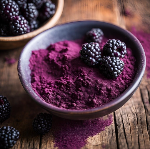 Purple berry powder in a dark bowl topped with fresh blackberries on a wooden table