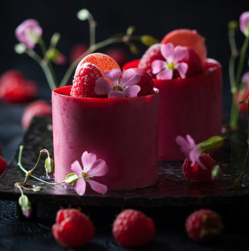 Red berry mini mousse cakes decorated with strawberries, raspberries and pink flowers